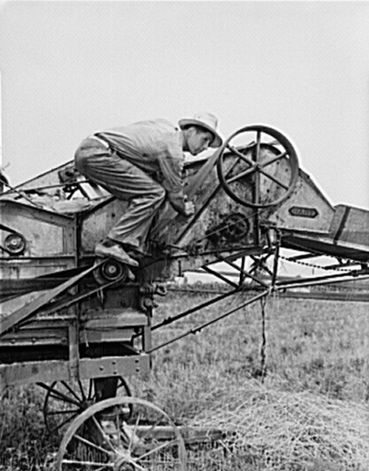 Michigan farmer fixing a belt 1940