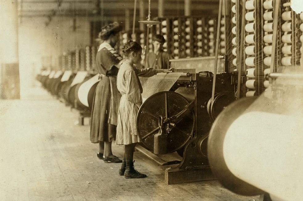 Girls running warping machines in Loray mill, Gastonia, N.C. Many boys and girls much younger. Boss carefully avoided them, and when I tried to get a photo which would include a mite of a boy working at a machine, he was quickly swept out of range. "He isn't working here, just came in to help a little." Location: Gastonia, North Carolina. Nov. 1908