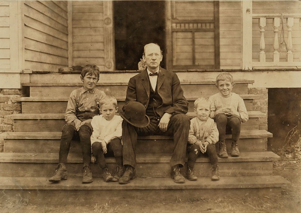 Mr. Smith, overseer in Wylie Mill, Chester, S.C. He will not let his children work in the mill. Says it is no place for them. Plenty of children below 12 in his mill. He said that it is a common practice all through the South for employers in cotton mills to evade the child labor law by allowing young children to help their older sisters or brothers. The name of the small child is not on the books. "That is the way we manage it." Nov. 28/08. Location: Chester, South Carolina Nov. 18, 1908 - Photo by Lewis Hines documenting child labor