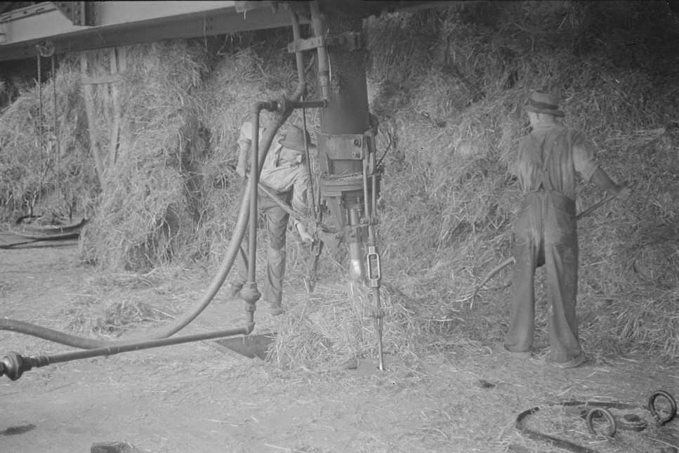 baled straw two men working