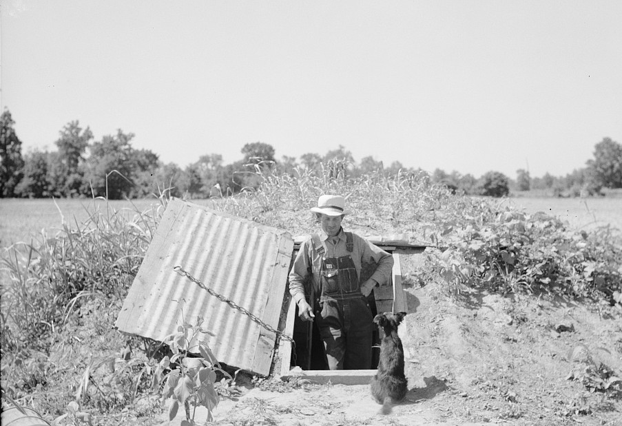 Rehabilitation Administration client standing in opening of storm cellar which is used also to store hundreds of cans of food. Near Batesville, Arkansas