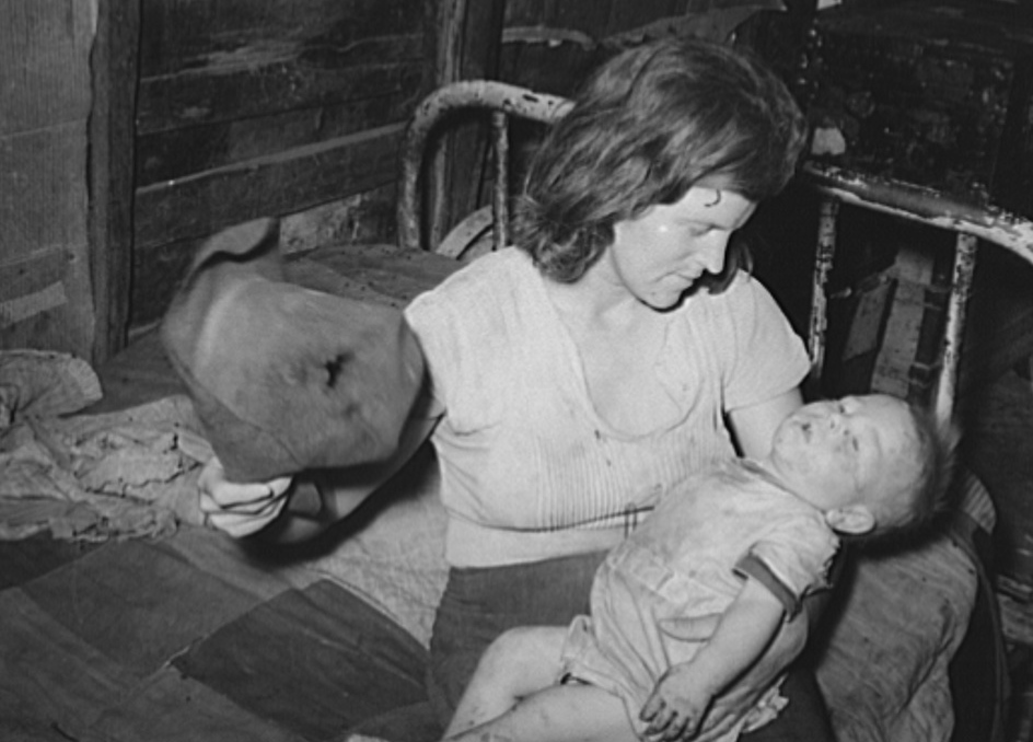 Mother fanning child with old hat to keep off flies. Mays Avenue camp, Oklahoma City,
